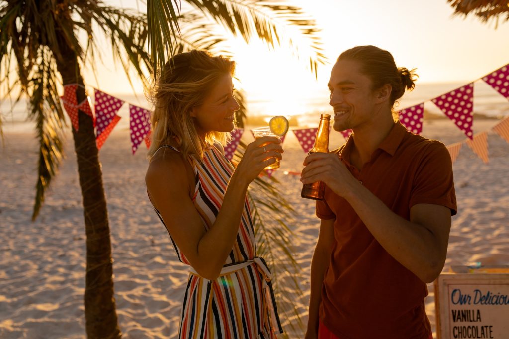 Caucasian couple smiling and drinking alcohol on beach