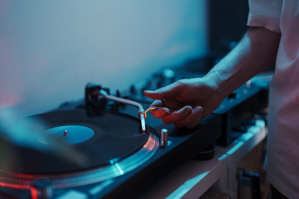 Dj placing needle on vinyl record at nightclub event